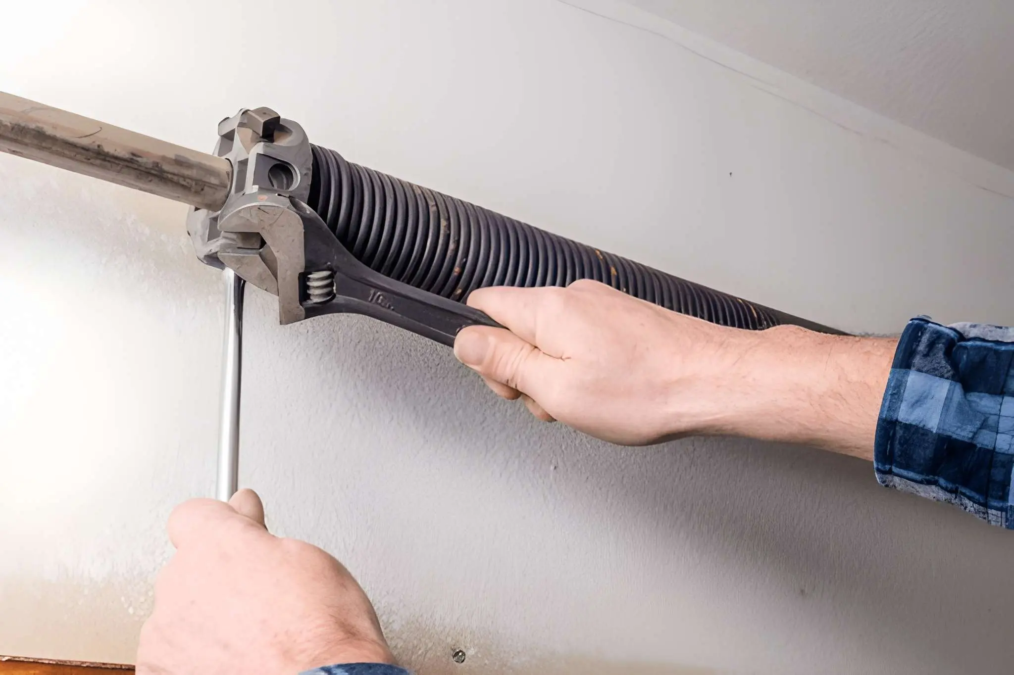 Technician safely replacing a broken garage door torsion spring